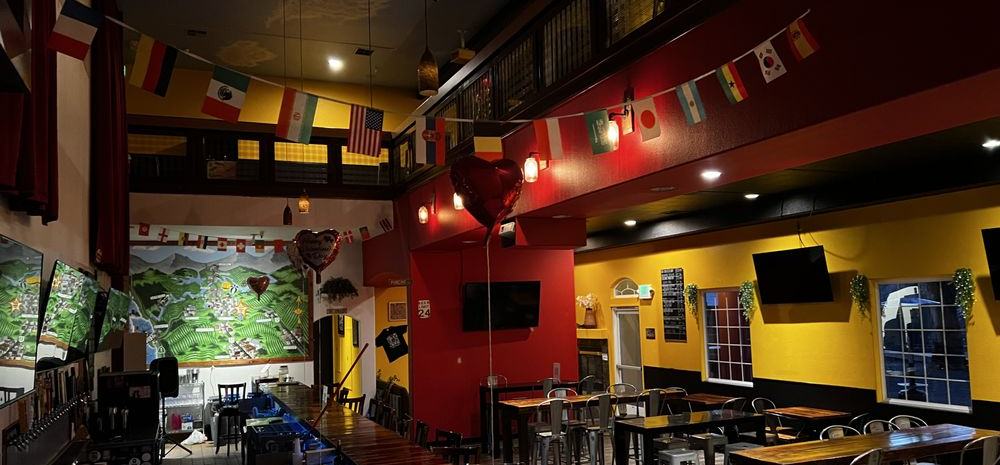El interior de Mr. Chile Taproom: la barra, las paredes rojas y amarillas y banderas de una docena de países