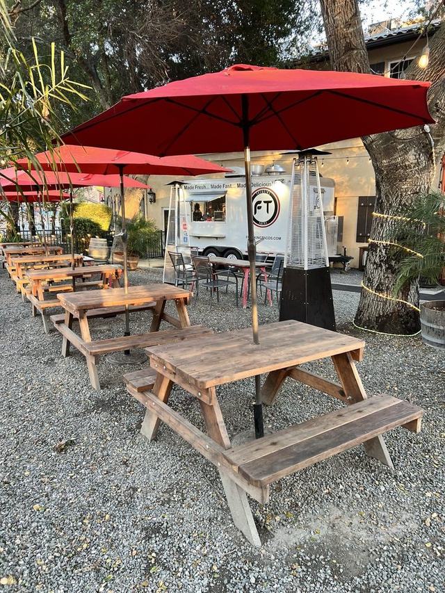 Red umbrellas over picnic tables with the taco truck behind